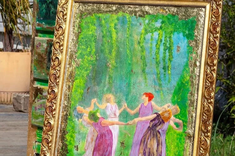 La Ronde des Équinoxes - Dans un écrin de verdure luxuriante, cinq femmes dansent en cercle, incarnant la célébration de la nature et des saisons. Leurs robes aux teintes violettes et rosées se mêlent aux feuillages, évoquant l'unité entre l'humain et le vivant. Cette ronde évoque la joie, la sororité et le lien ancestral avec les rythmes de la Terre. Le cadre doré orné de motifs floraux renforce le caractère précieux de cette scène presque onirique, entre Art Nouveau et poésie symboliste. - Titre : La Ronde des Équinoxes Artiste : Kouleur Bohème Technique : Peinture mixte sur support ancien / technique mixte et revalorisation artistique Encadrement : Cadre ancien restauré, doré, ornementé Adopté par : Château de Lescurie Année : 2025 