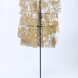 Ajourages, II, 2022-2023 - Ajourages est une série de vêtements-sculpture en hommage aux faïenceries Sarthoises dont les techniques sont en voie de disparition. La transmission de ce geste artisanal de femmes en manufactures esquisse la promesse fragile d'un futur proche où corps et décor se réparent puis se « re-parent » ensemble. Il s'agissait alors de produire un objet que l'on puisse emporter avec soi lorsqu'il faut quitter les lieux, ainsi transporter la manufacture, son silence, ses ombres et ses lumières. À présent, ces vêtements-sculpture prennent vie dans le cadre de performances-poésie, comme des architectures fragiles qui accueillent le son des voix en résonnance avec la musique des pièces assemblées qui s'entrechoquent dans les déplacements. Les vêtements, portés à la tombée de la nuit deviennent alors des armures, le sanctuaire d'âmes qui déambulent, aux corps dévoilés en partie par le travail des jours sur les éléments de faïence. - Nàto Bosc-ducros 