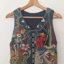 sort du coeur - broderie sur gilet type serveur, motifs végétaux denses, squelette et personnage nu.