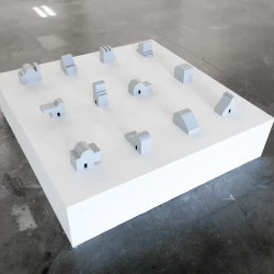Maisons Grises - Déclinaison de douze maquettes de maison. En partant des bases fondamentales d'une habitation, qui sont visuellement des murs, une porte et un toit, comment je peux jouer sur la transformation des murs, qui, suivant le patron géométrique choisi, nous renvoie à des architectures familières ? Ces formes une fois produites nous ramènent à l'idée d'artefact. (dimension : variables / médium : Carton, colle, bombe de peinture : date : 2023 - Crédit photo : Zachary Toulemont / Oeuvre : Anouk Glorieux 